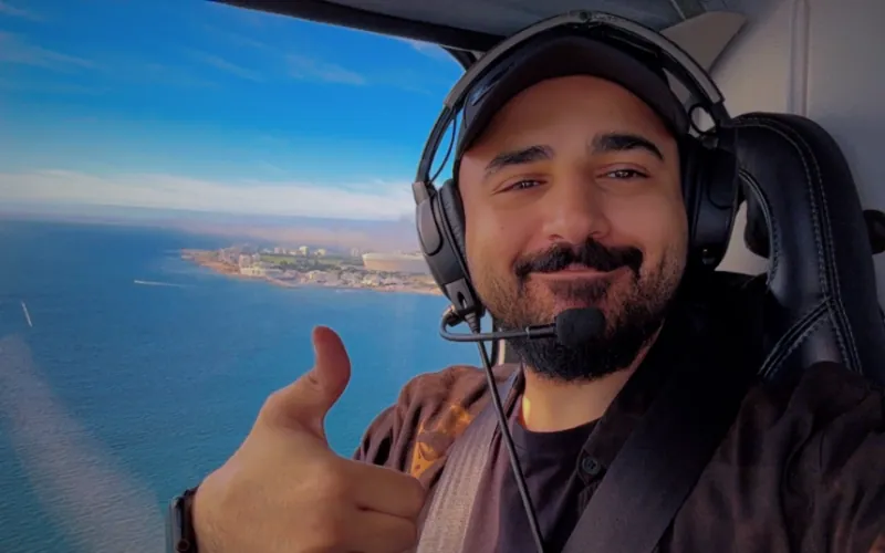 Rayan Alajmi giving a thumbs-up during a flight over the coast